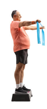 A senior man is standing on an exercise step using stretch bands to work out his back and arms
