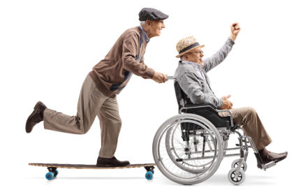 A senior man on a skateboard is pushing another senior man in a wheelchair